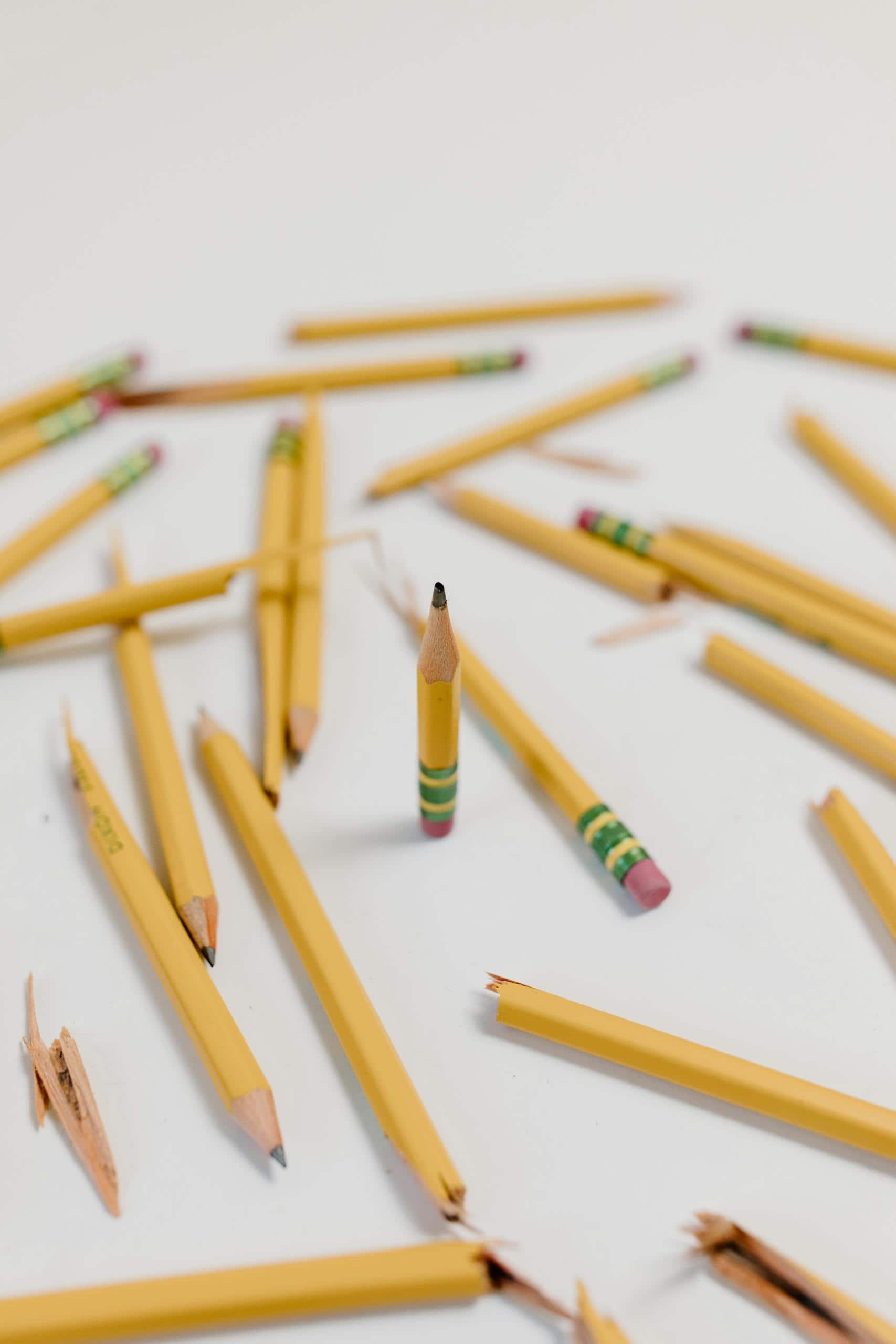 A creatively arranged set of broken and whole yellow pencils on a white background, emphasizing selective focus.
